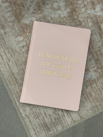Pink notebook with gold text on a textured surface Beautiful Girl Fabric Journal