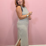 Black and white sleeveless striped midi dress worn by a woman against a pink wall