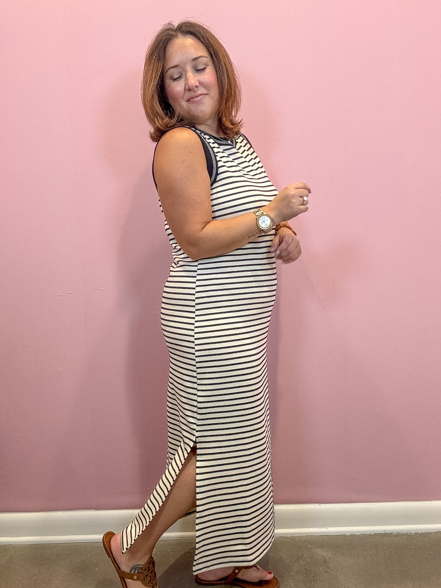 Black and white sleeveless striped midi dress worn by a woman against a pink wall