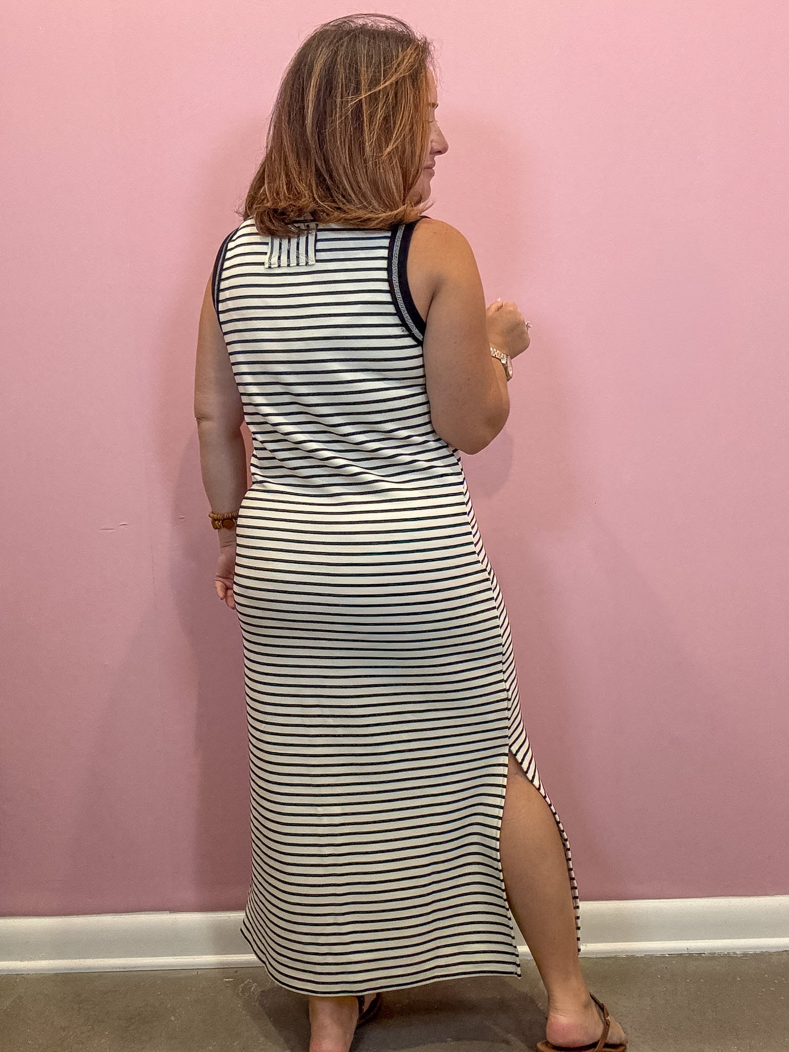 Black and white sleeveless striped midi dress worn by a woman against a pink wall