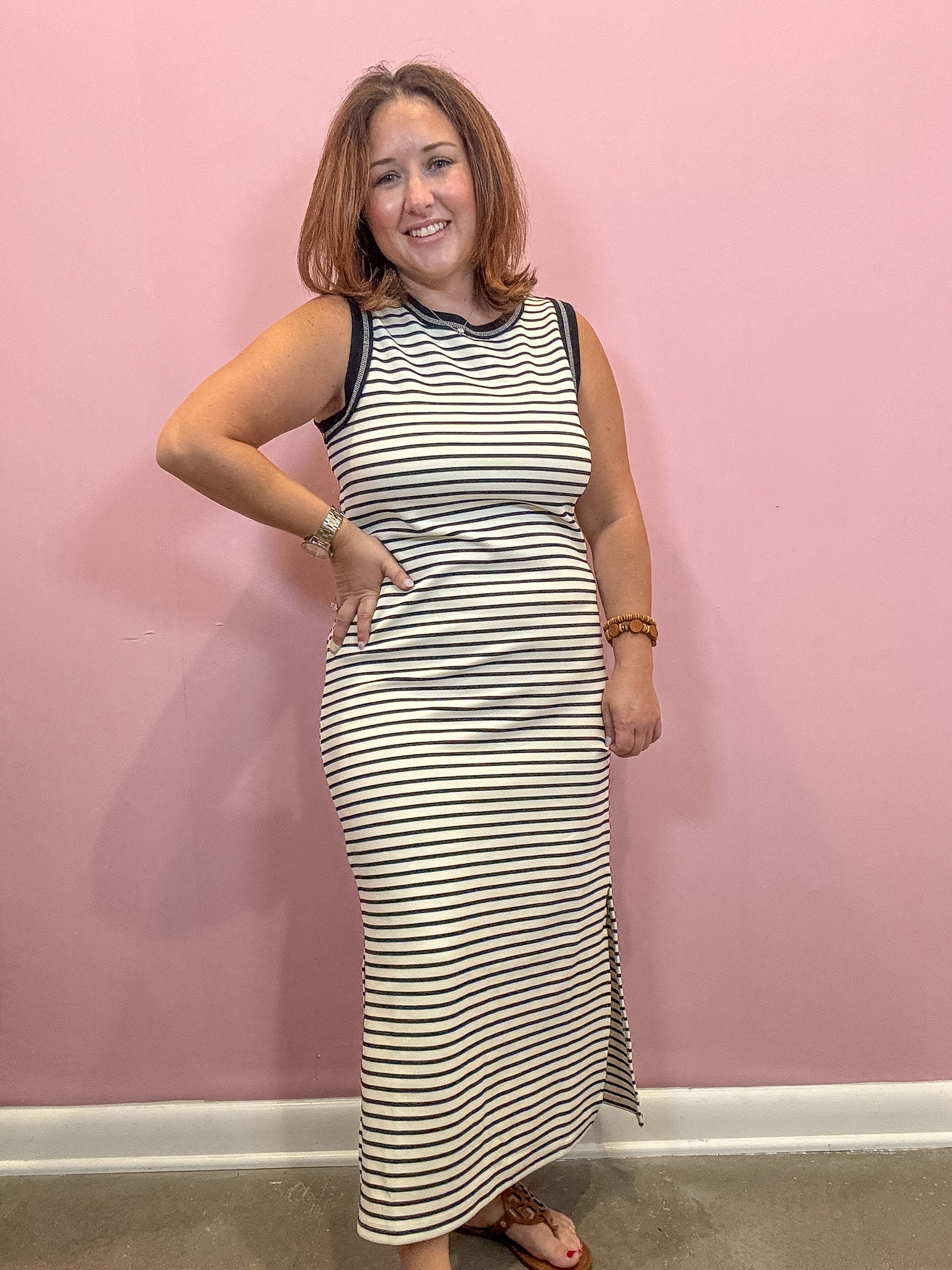 Black and white sleeveless striped midi dress worn by a woman against a pink wall
