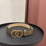 A beige leather belt with a gold-tone interlocking double-O chain buckle, displayed on a round black side table.