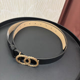 A black leather belt with a gold rope-textured double-O buckle, displayed on a round black tray.