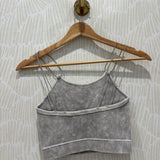 A gray ribbed knit camisole tank top with thin straps and horizontal seam detailing, hanging on a wooden hanger against a patterned wallpaper background.
