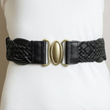 A black braided leather belt with a central antique gold oval buckle, displayed on a white mannequin torso.
