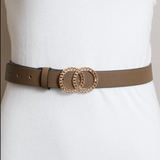 A slim brown leather belt with a double interlocking rope-textured gold-tone buckle, shown worn on a white dress form.